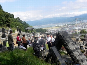 写真　諏訪湖を望む顕彰碑に花を手向け千代子のたたかいに思いを馳せる