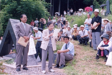 写真　碑前祭であいさつする小市草子さん