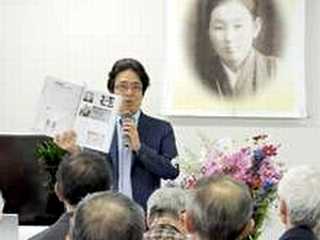 写真　中学校の教科書を示しながら講演する本庄さん